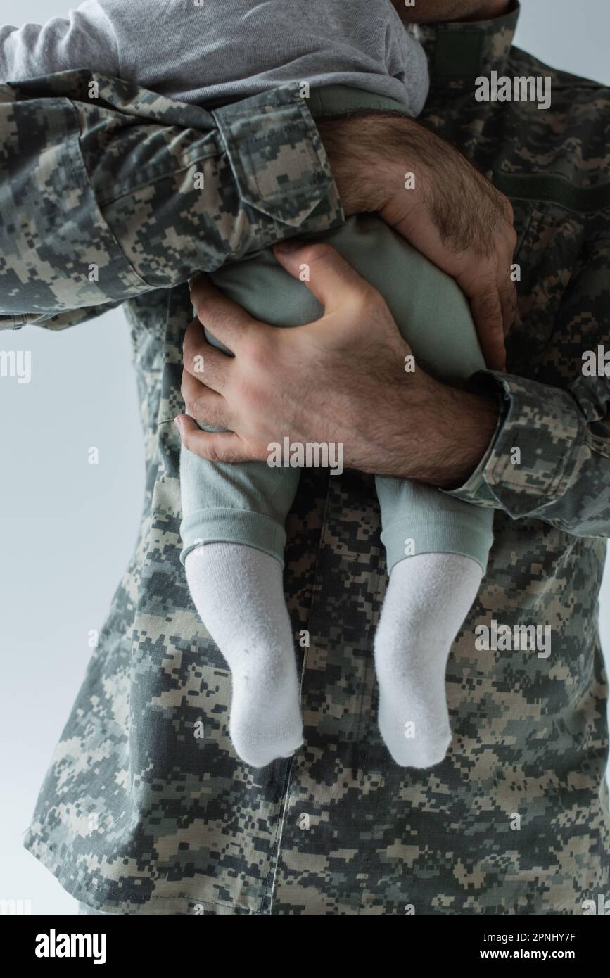 cropped view of father in military uniform hugging infant son isolated