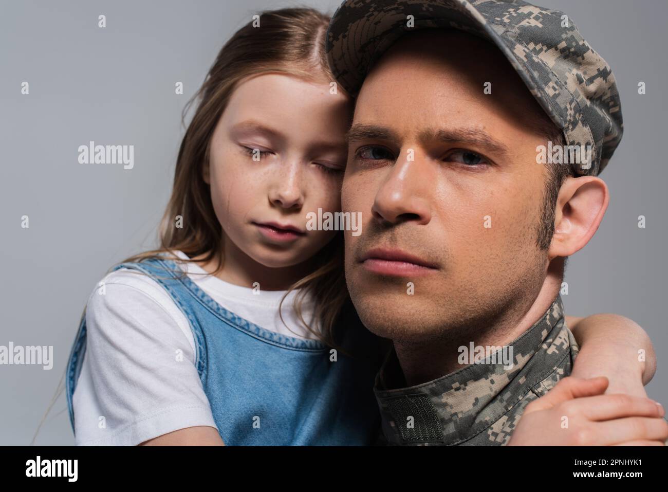 sad girl hugging father in military uniform and crying during memorial day isolated on grey Stock Photo