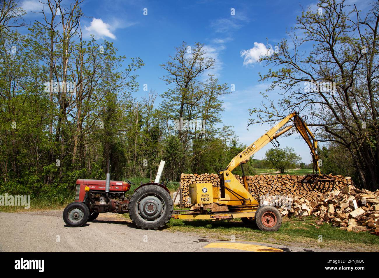 Old agricultural tractor with crane for loading wood log Stock Photo