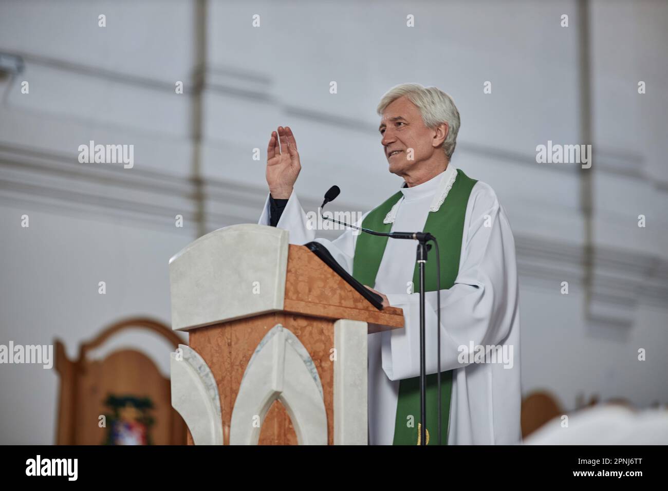 Senior priest in formalwear standing behind the altar and blessing