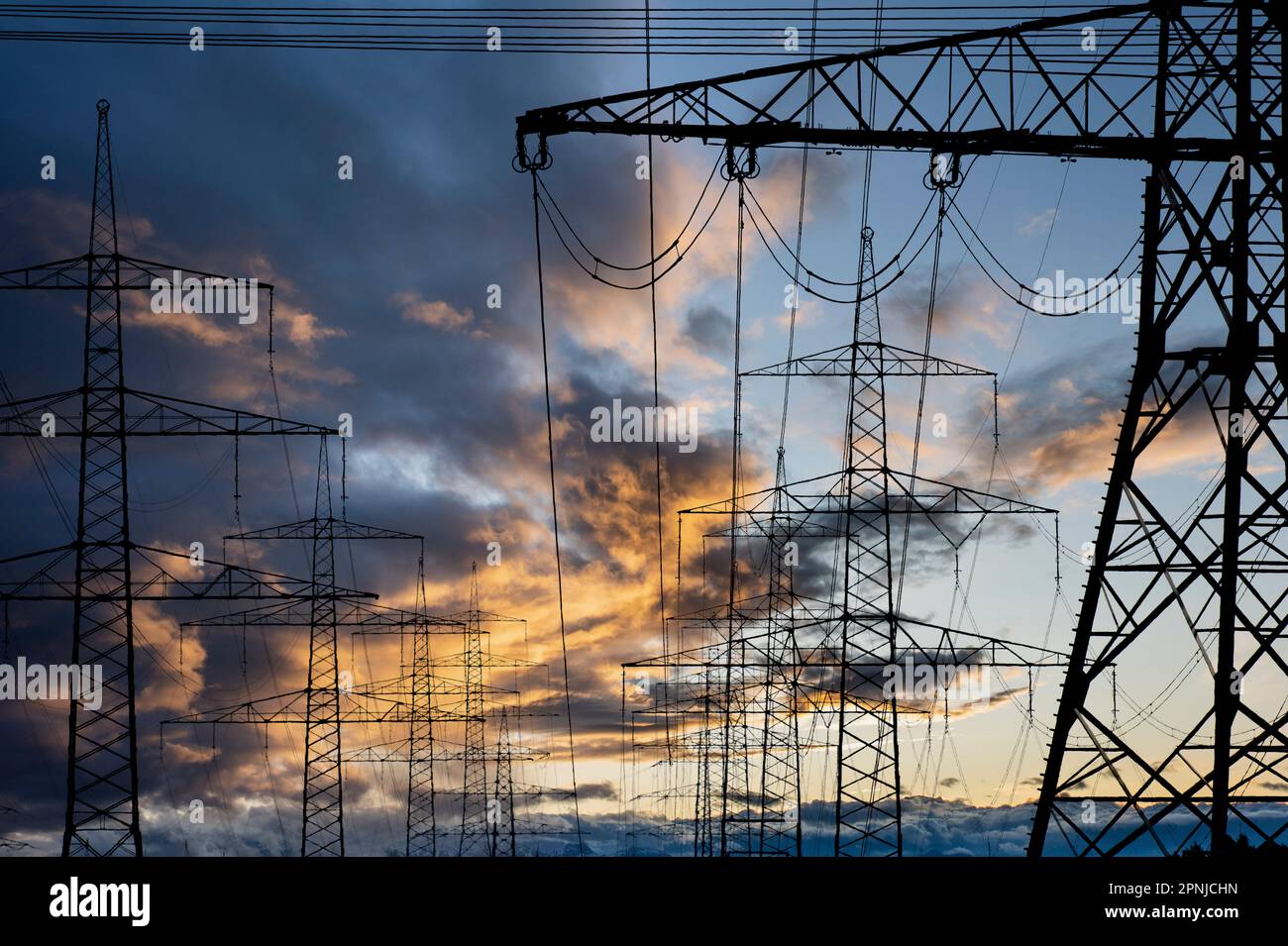 high voltage pylons for electricity and power against sky with dramatic clouds Stock Photo