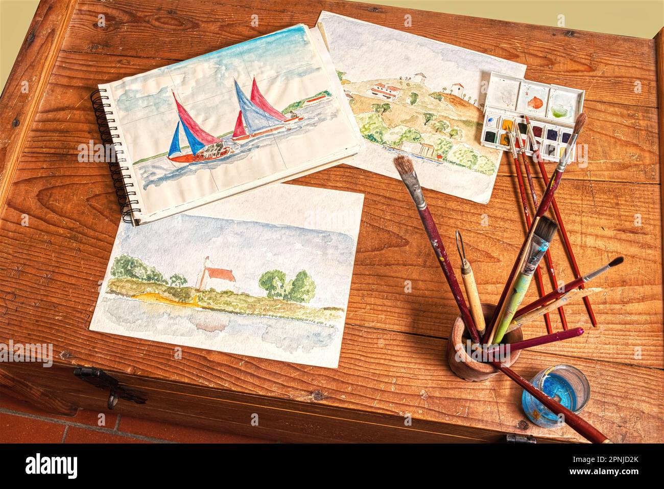 Watercolor painting, a light and immediate way to record your travel impressions. Some artwork and tools on a rustic wooden chest of drawers. Stock Photo