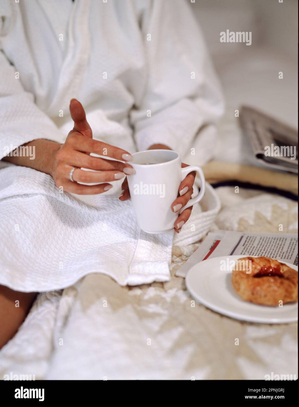 Woman in white robe having breakfast on bed Stock Photo
