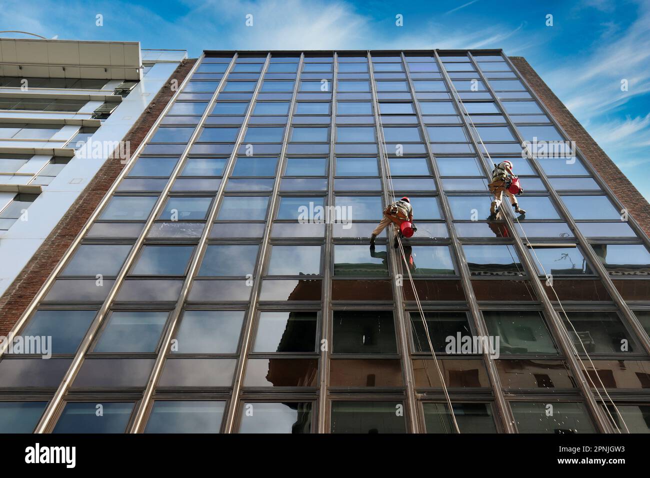 two men cleaning the windows on the heights of a skyscraper Stock Photo