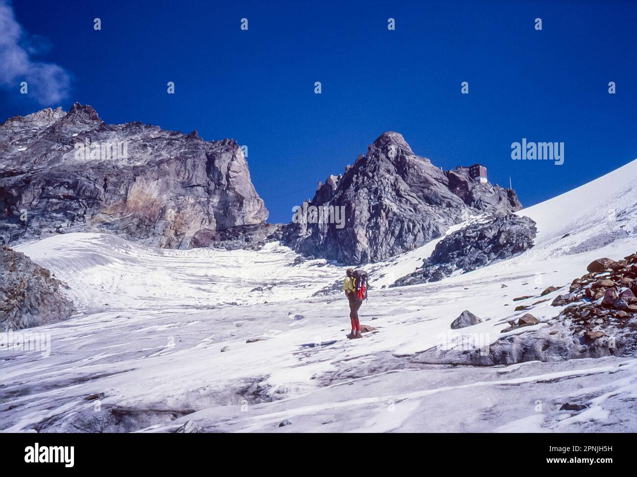 A lone climber makes the approach to the Swiss Alpine Club hut Cabane Bertol perched high on the ridge on the Chamonix to Zermatt Haute Route Stock Photo