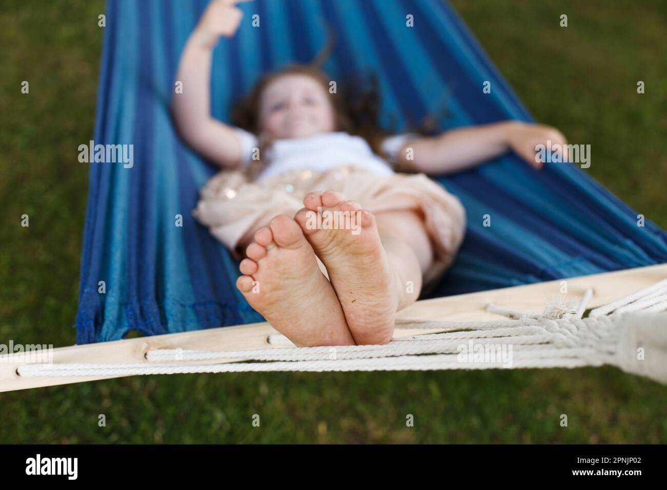 closeup of little girl's feet relaxing in the blue hammock during her