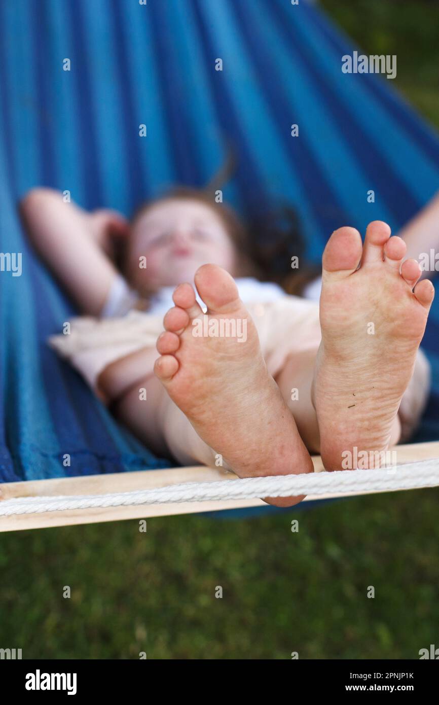 closeup of little girl's feet relaxing in the blue hammock during her