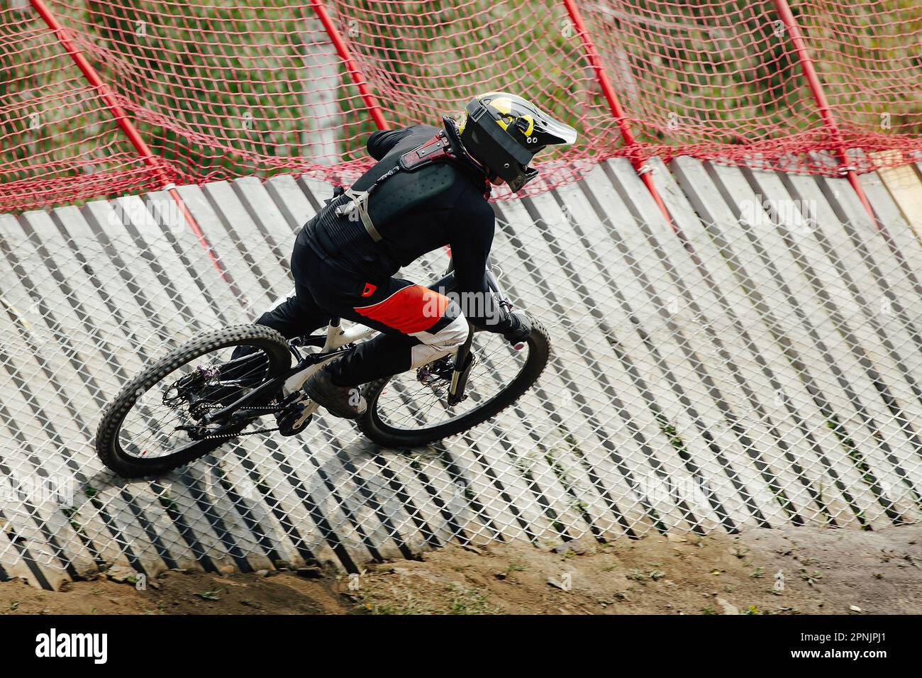 male rider rips turn on wood insloped corner in downhill race, summer extreme sports Stock Photo