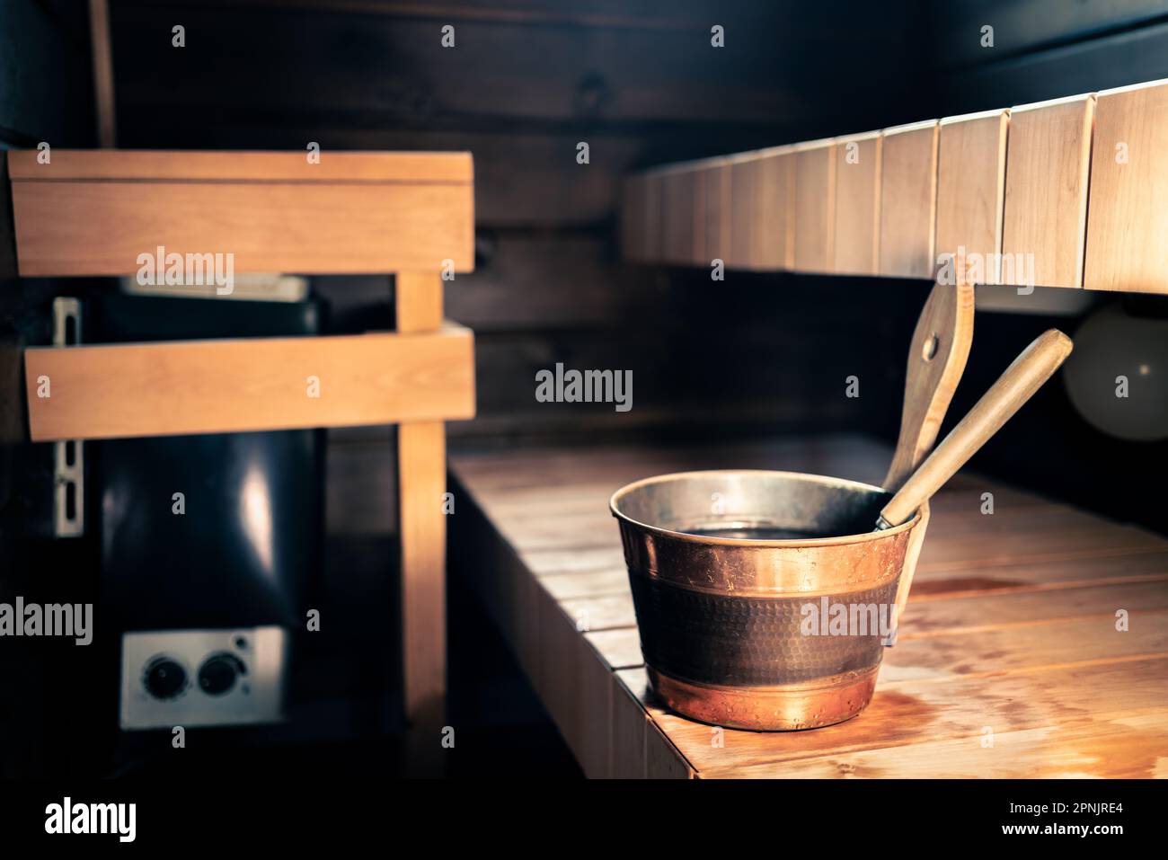 Sauna, spa wellness steam room in Finland. Wooden summer cabin interior. Electric stove in city home or hotel. Ladle and water bucket. Health bath. Stock Photo