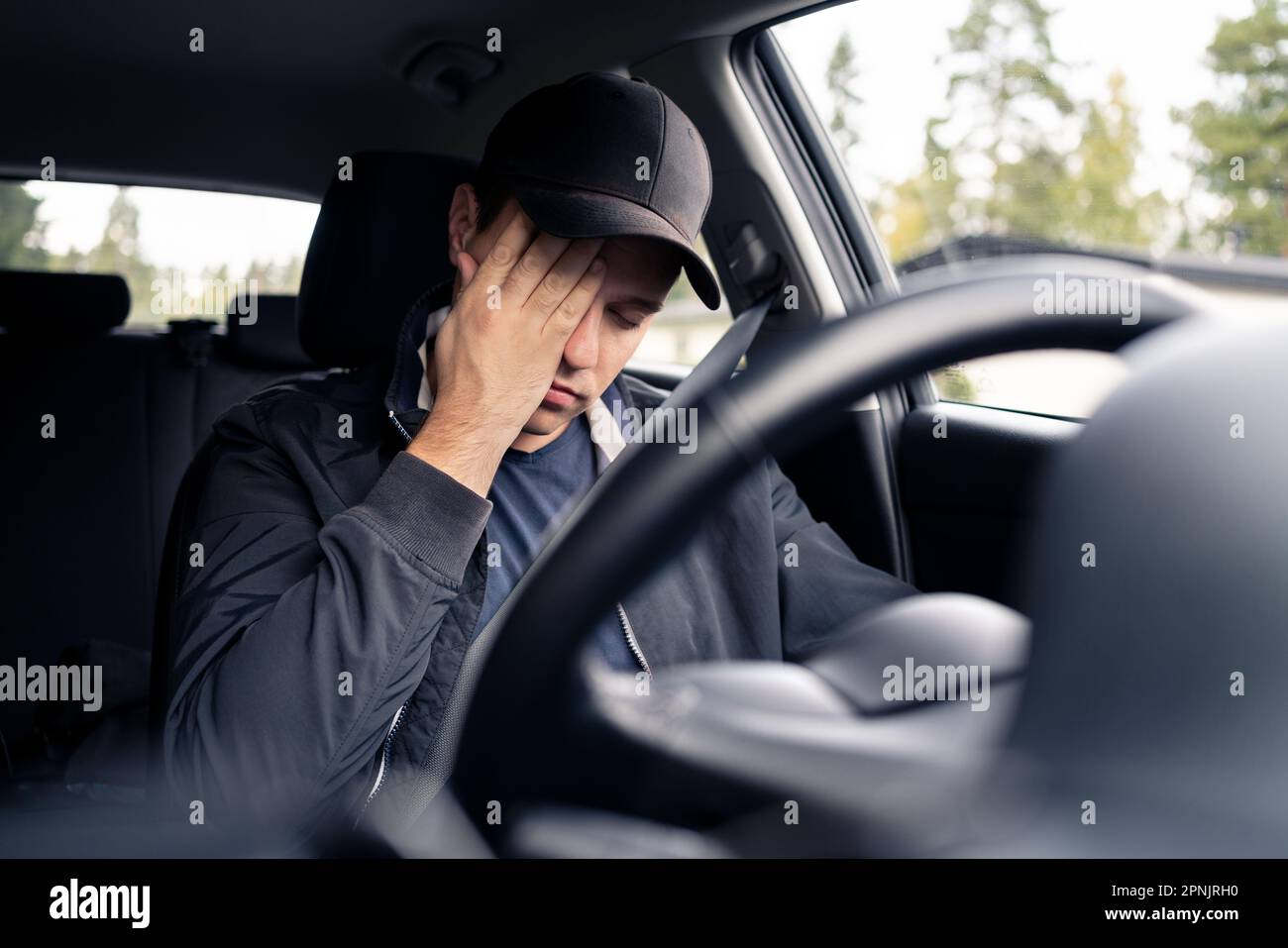 Tired man in car. Sleepy drowsy driver, fatigue. Driving and sleeping in vehicle. Exhausted, bored or drunk person. Serious upset man with stress. Stock Photo