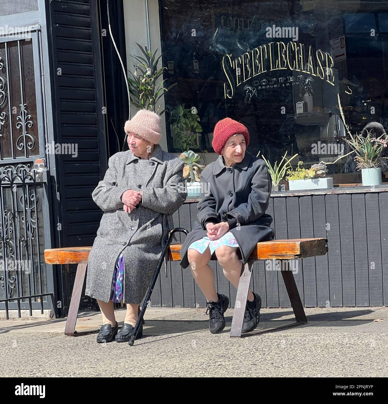 Two older women sitting in the early spring sun in front of the SteepleChase Cafe in in the Windsor Terrace neighborhood of Brooklyn, New York. Stock Photo