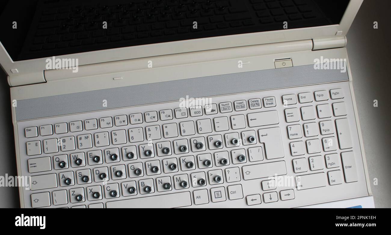 Top view of laptop with iron nuts overlay a russian letters on keyboard buttons Stock Photo