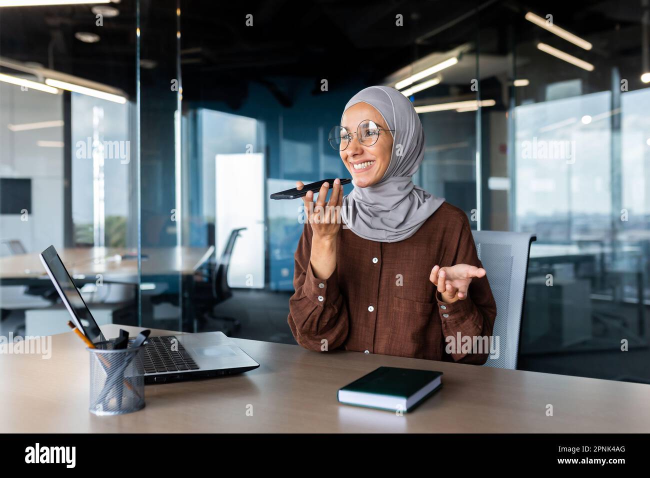 Young Muslim woman freelancer in hijab sitting at office desk in front ...