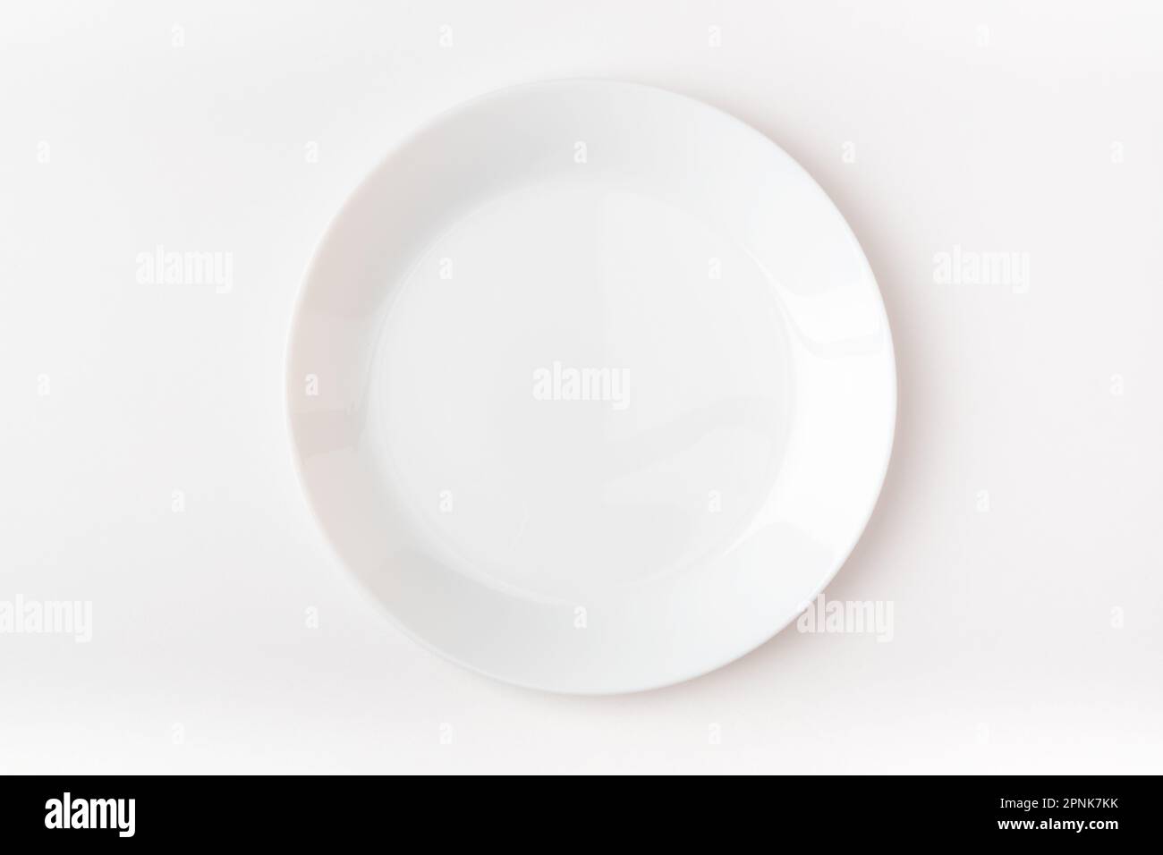 An empty white plate on a white background. Blank plate. Top view. Stock Photo