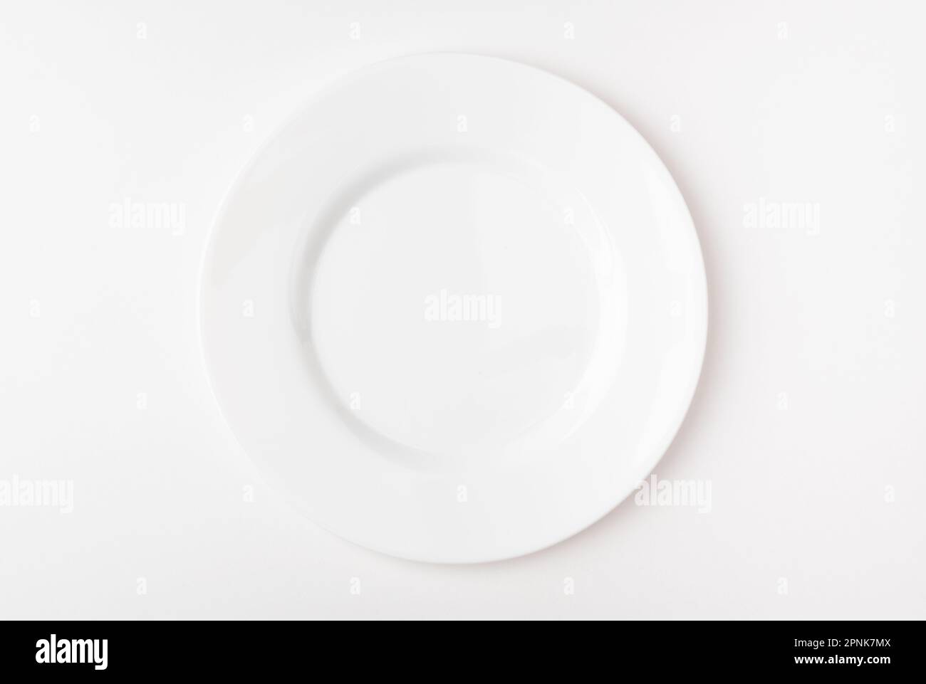 An empty white plate on a white background. Blank plate. Top view. Stock Photo