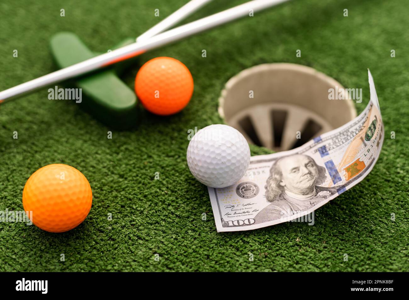 Mini Golf club, ball and money on the artificial grass Stock Photo