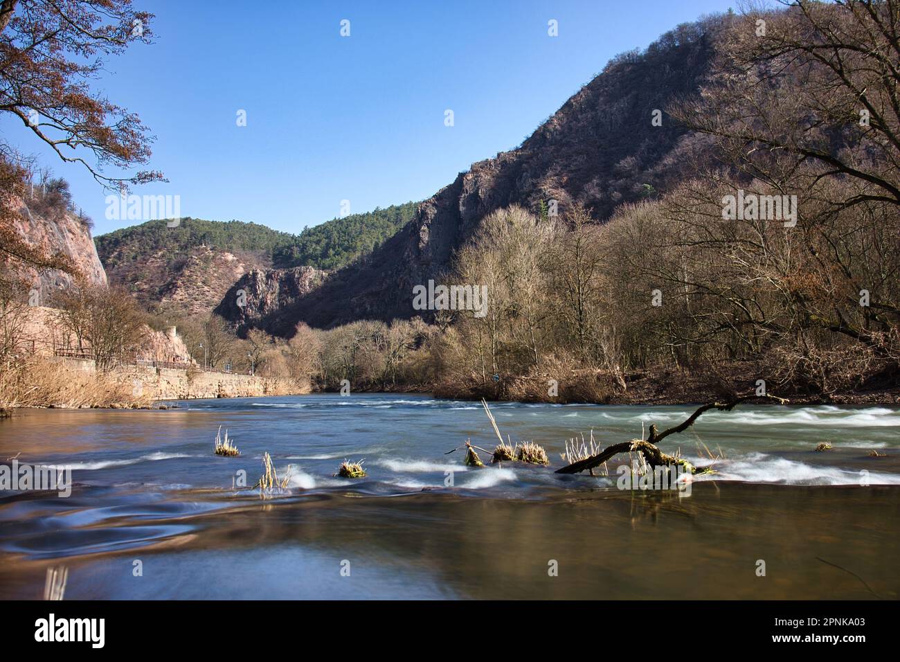 Water running in the Nahe River on a sunny winter day in Bad Kreuznach with hills in Rotenfels in the background. Stock Photo