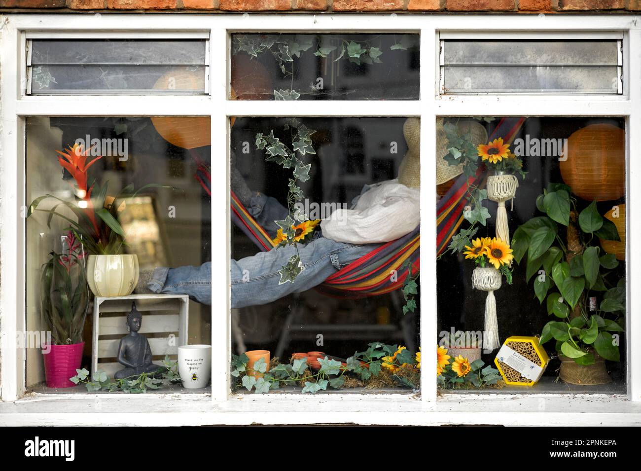 Florist shop window display with mannequin resting in a hammock Stock
