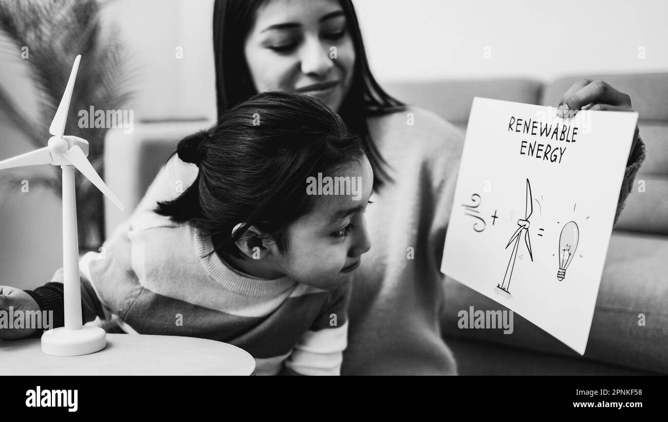 Asian mother working with her child on renewable energy project for school science class at home - Focus on windmill drawing - Black and white editing Stock Photo
