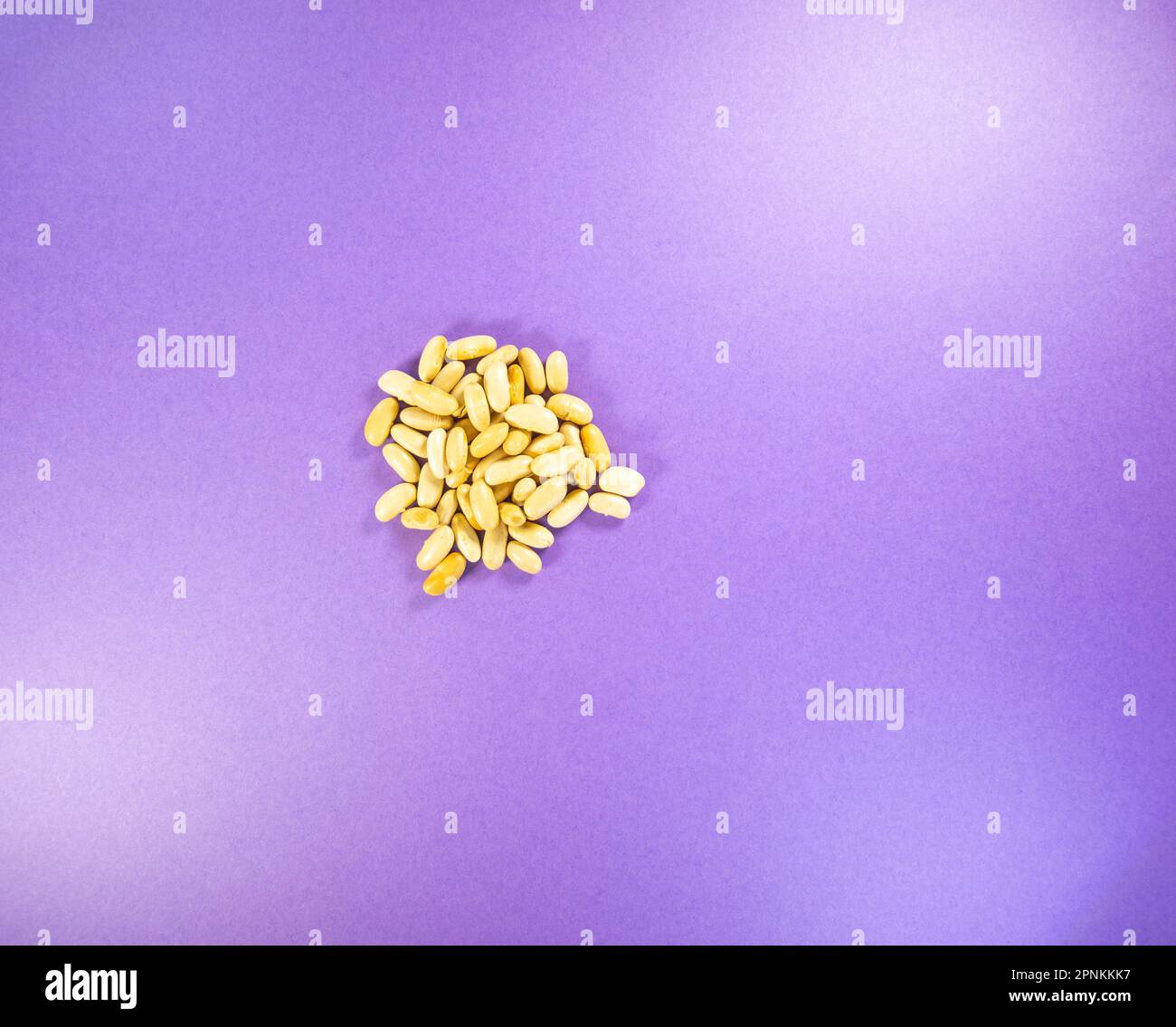 small heap of used (for blind baking) navy bean, haricot, pearl haricot bean isolated on a purple background Stock Photo