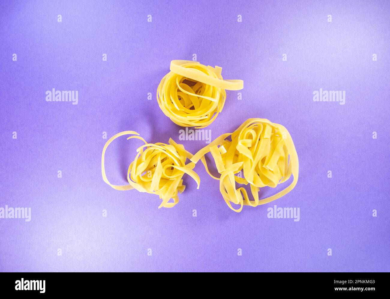 three pasta nests of tagliatelle isolated on a purple background Stock ...