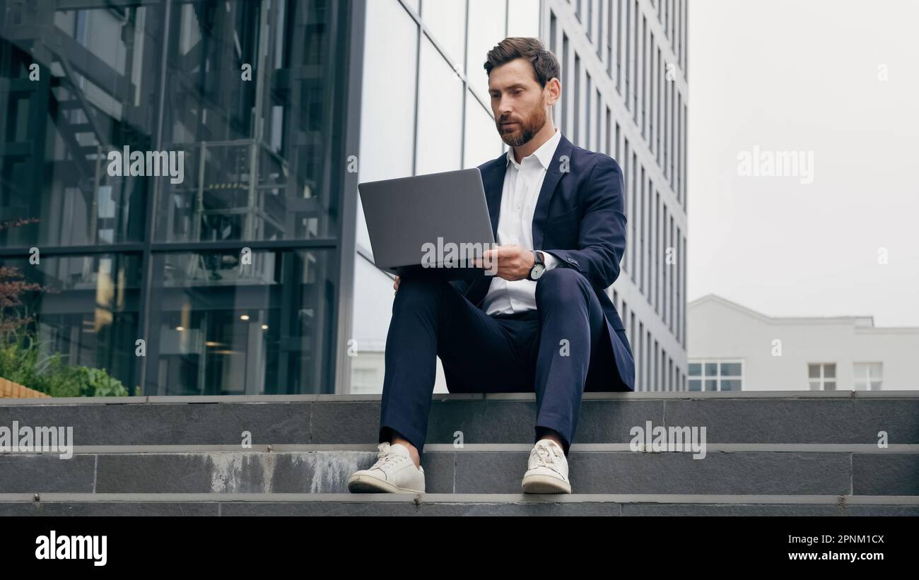 Successful businessman talking on video call on laptop negotiating conducting interview outdoors via online conference young male professional worker Stock Photo