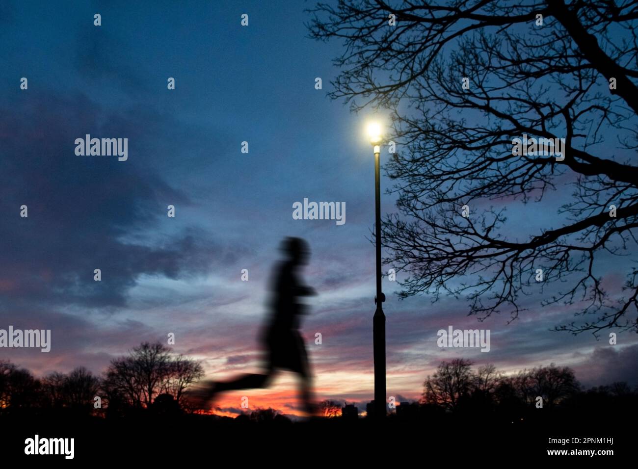 Running to keep fit in a London park at sunset Stock Photo