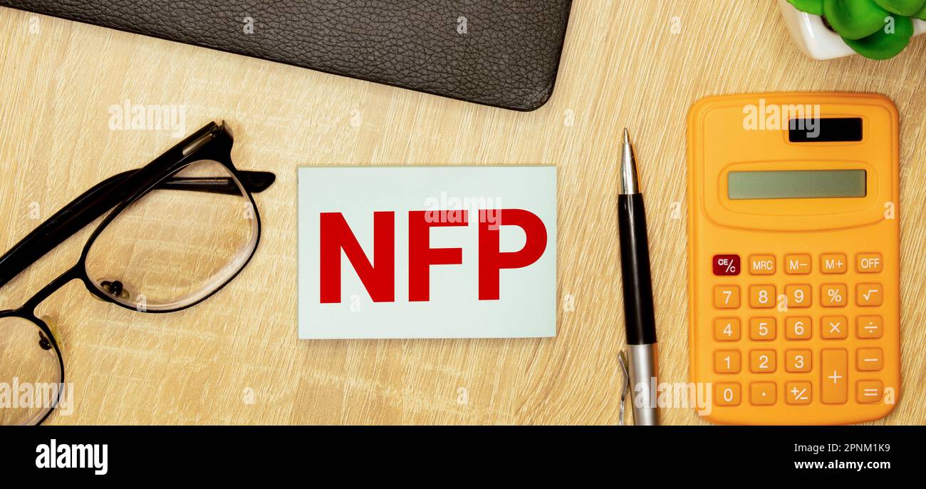 Selective focus of pens, clock, money banknote and notebook written with text NFP stands for Nonfarm payrolls. Business concept. Stock Photo