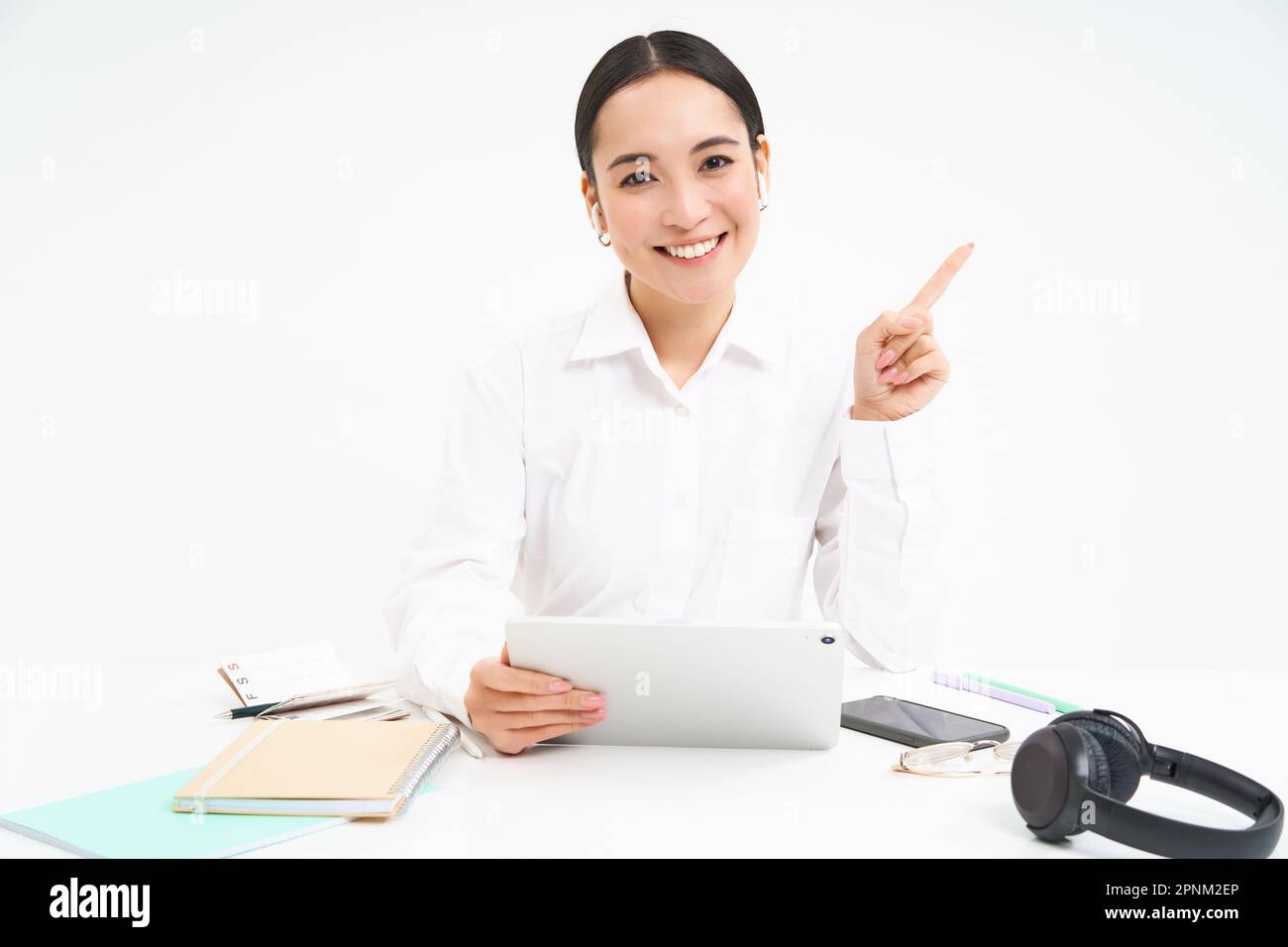 Portrait of young asian woman sitting in office, holding tablet and ...