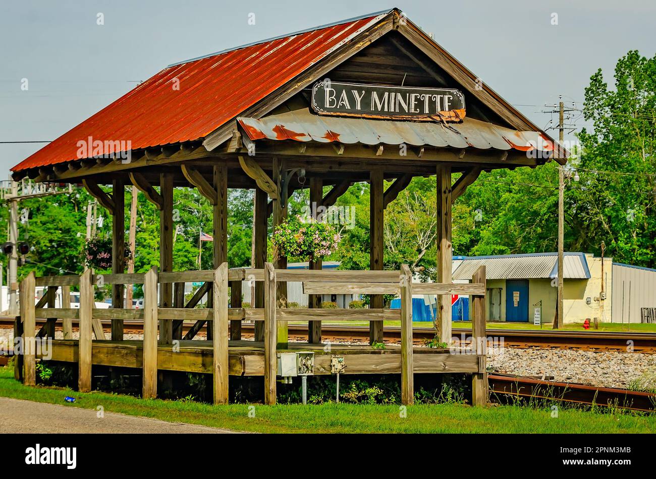 A rustic wooden platform stands alongside the railroad tracks near the
