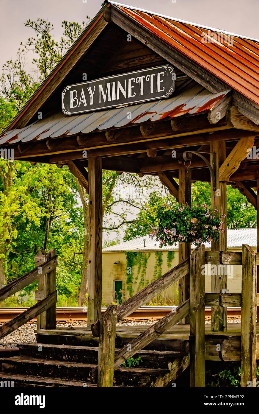 A rustic wooden platform stands alongside the railroad tracks near the