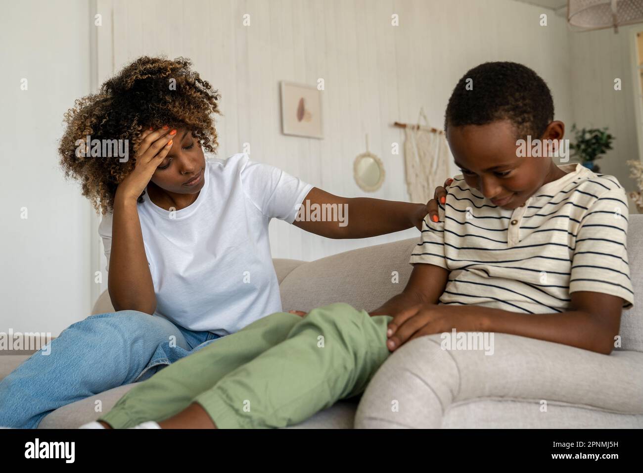 Naughty mischievous mixed race child boy smiles maliciously in response to tired mother moralising Stock Photo
