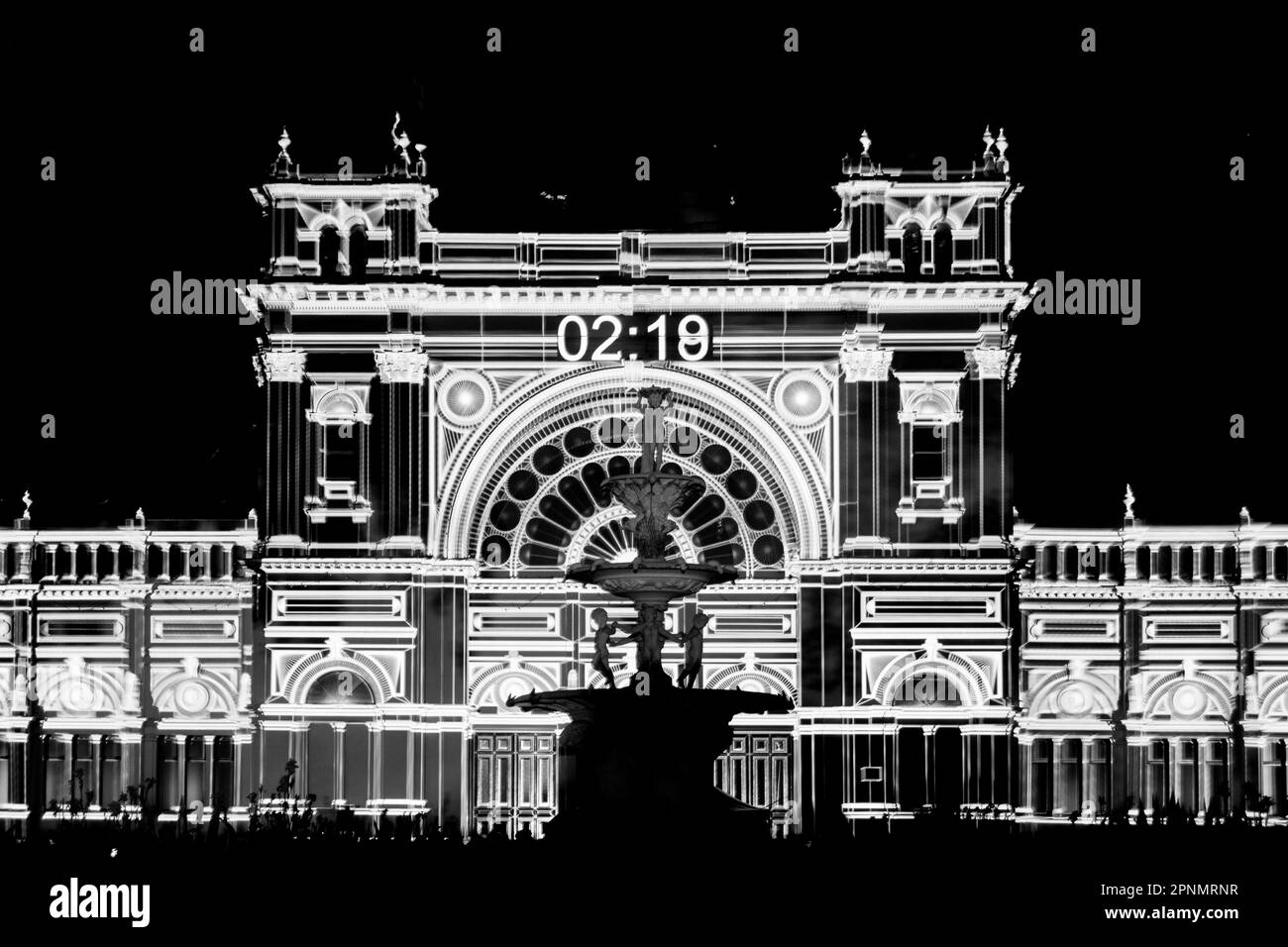 A black and white photo of a building during a light show / display at