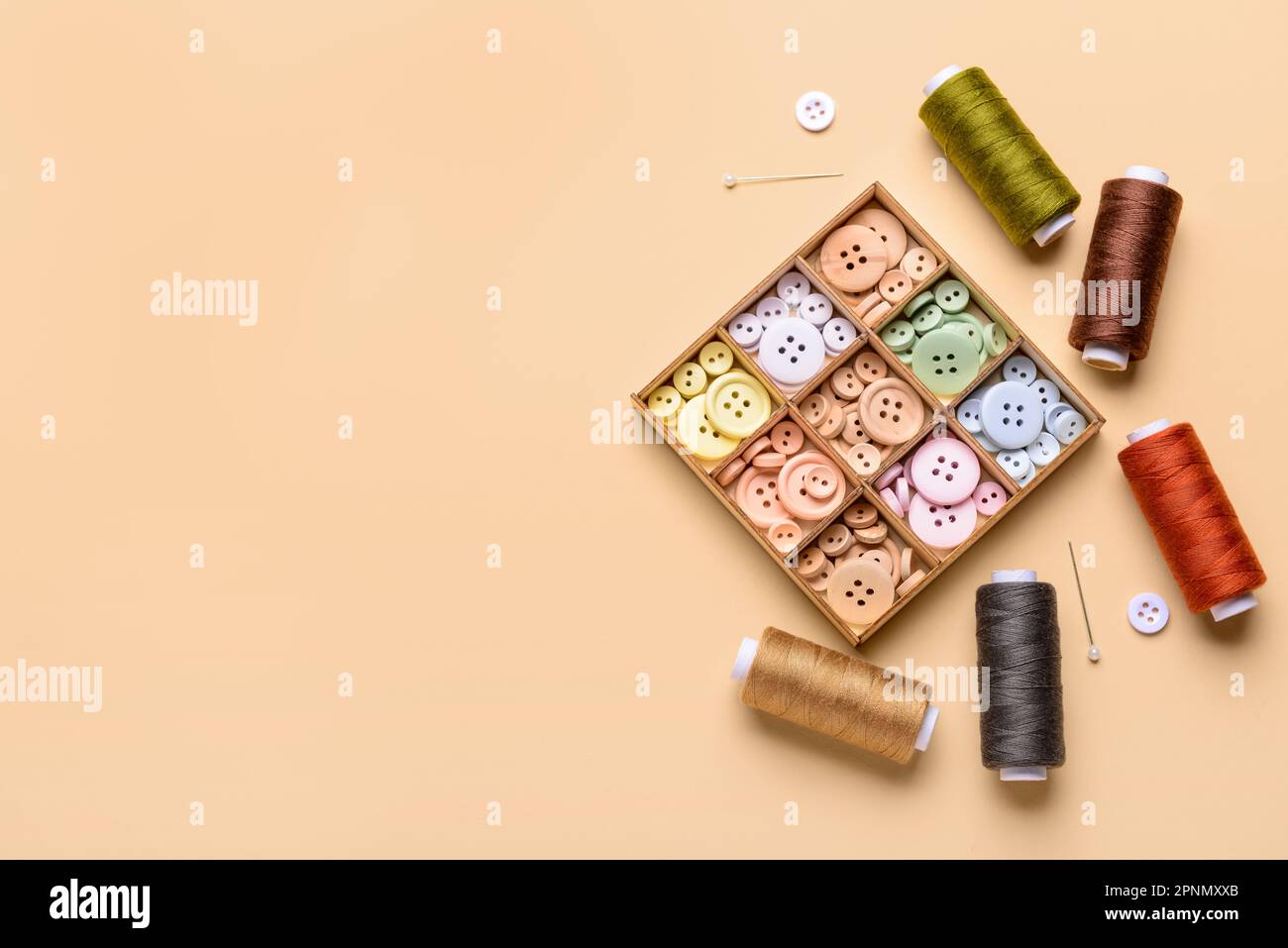 Composition with different buttons, thread spools and ball pins on color background Stock Photo