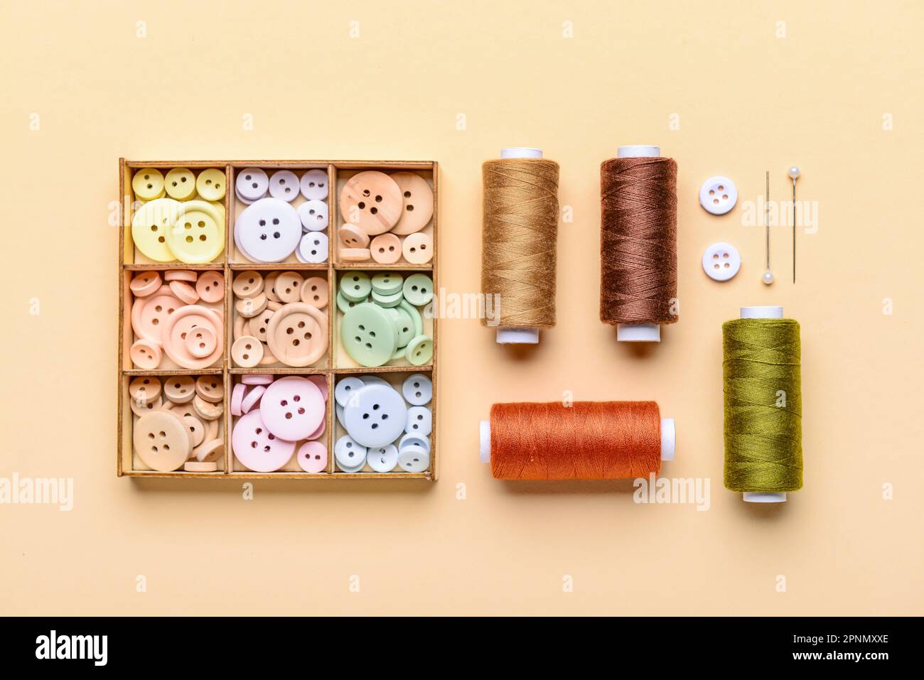 Composition with different buttons and thread spools on color background Stock Photo