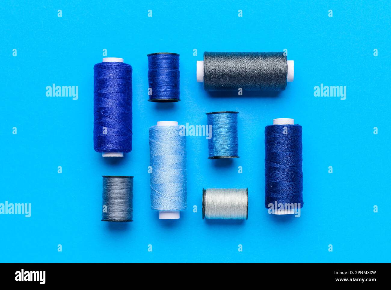 Composition with different thread spools on color background Stock Photo