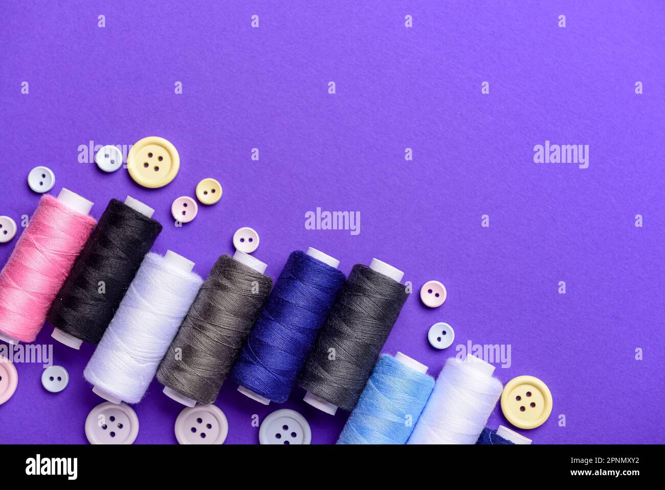 Composition with different thread spools and buttons on color background Stock Photo