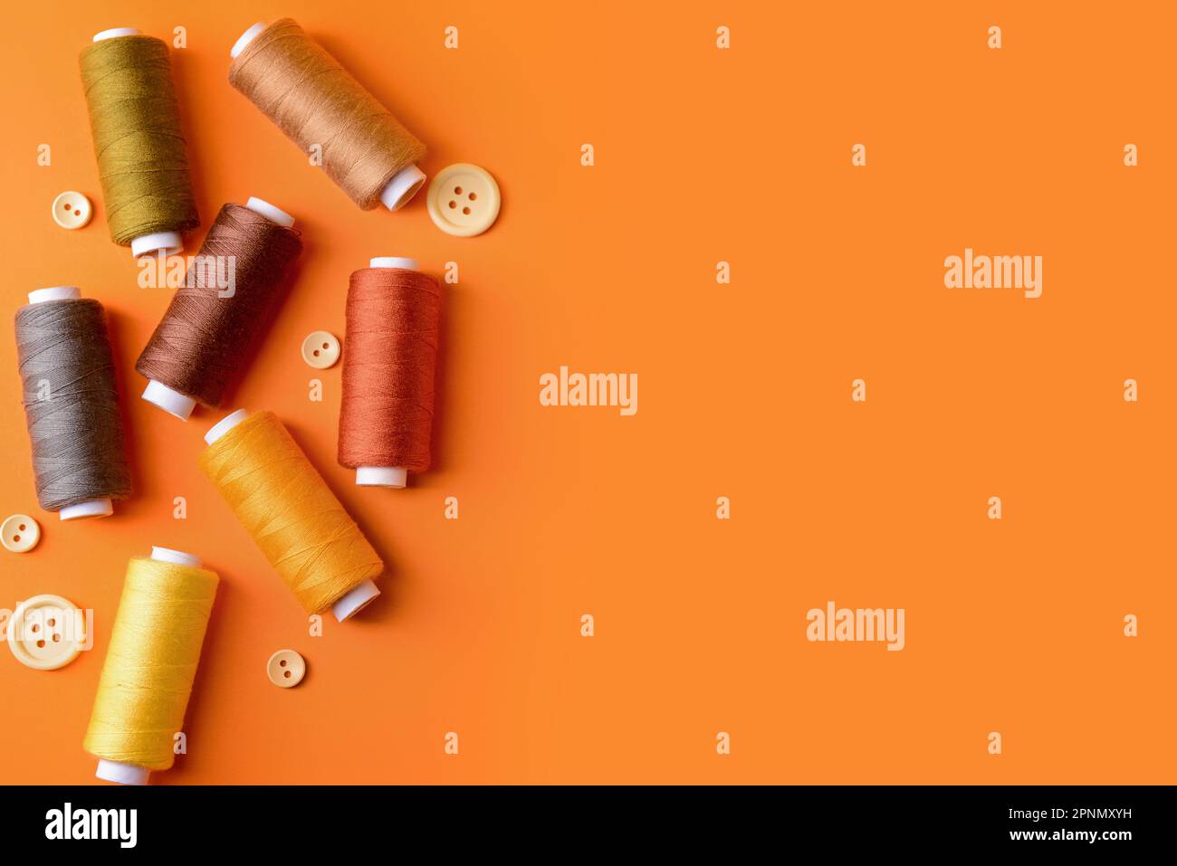 Composition with different thread spools and buttons on color background Stock Photo