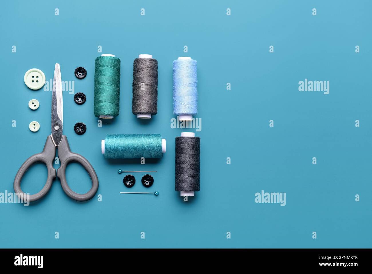Composition with thread spools, buttons and scissors on color background Stock Photo