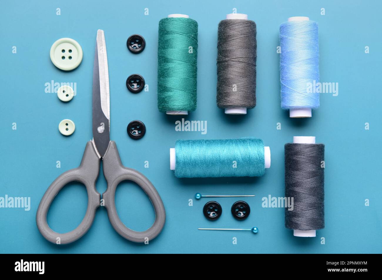 Composition with thread spools, buttons, scissors and ball pins on color background Stock Photo