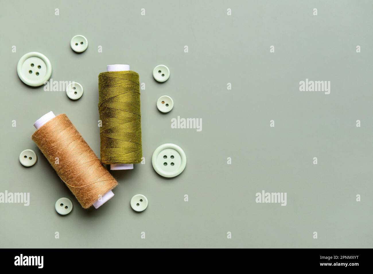 Composition with thread spools and buttons on grey background Stock Photo