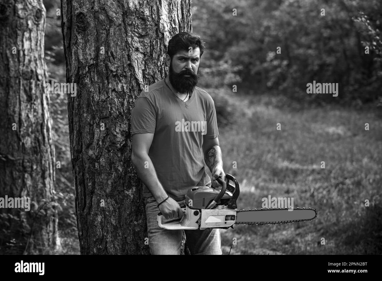 Lumberjack worker with chainsaw in the forest. Handsome young man with