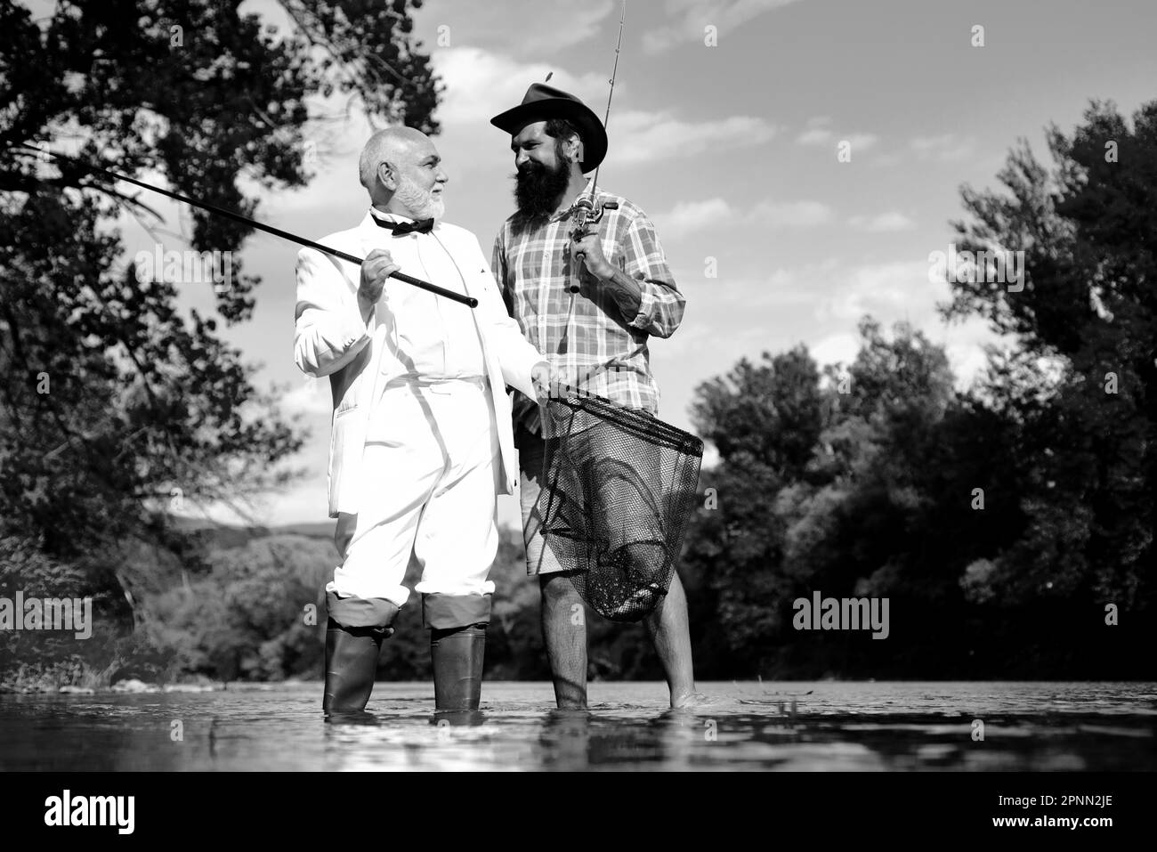 Happy bearded fishers in water. Senior man in suit with rod and fish