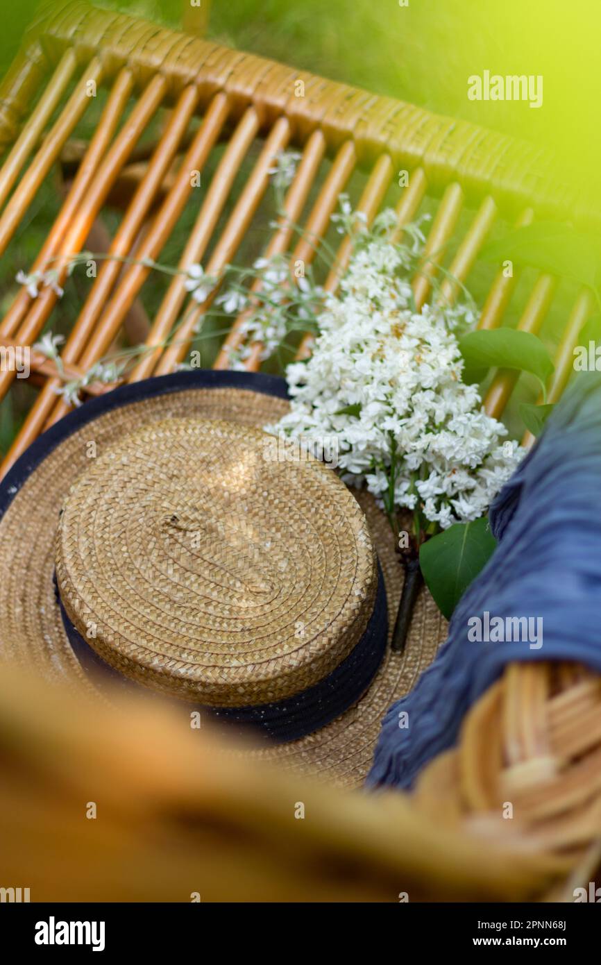Slow life. A straw hat with flowers lies on a wicker chair. View from above. Stock Photo