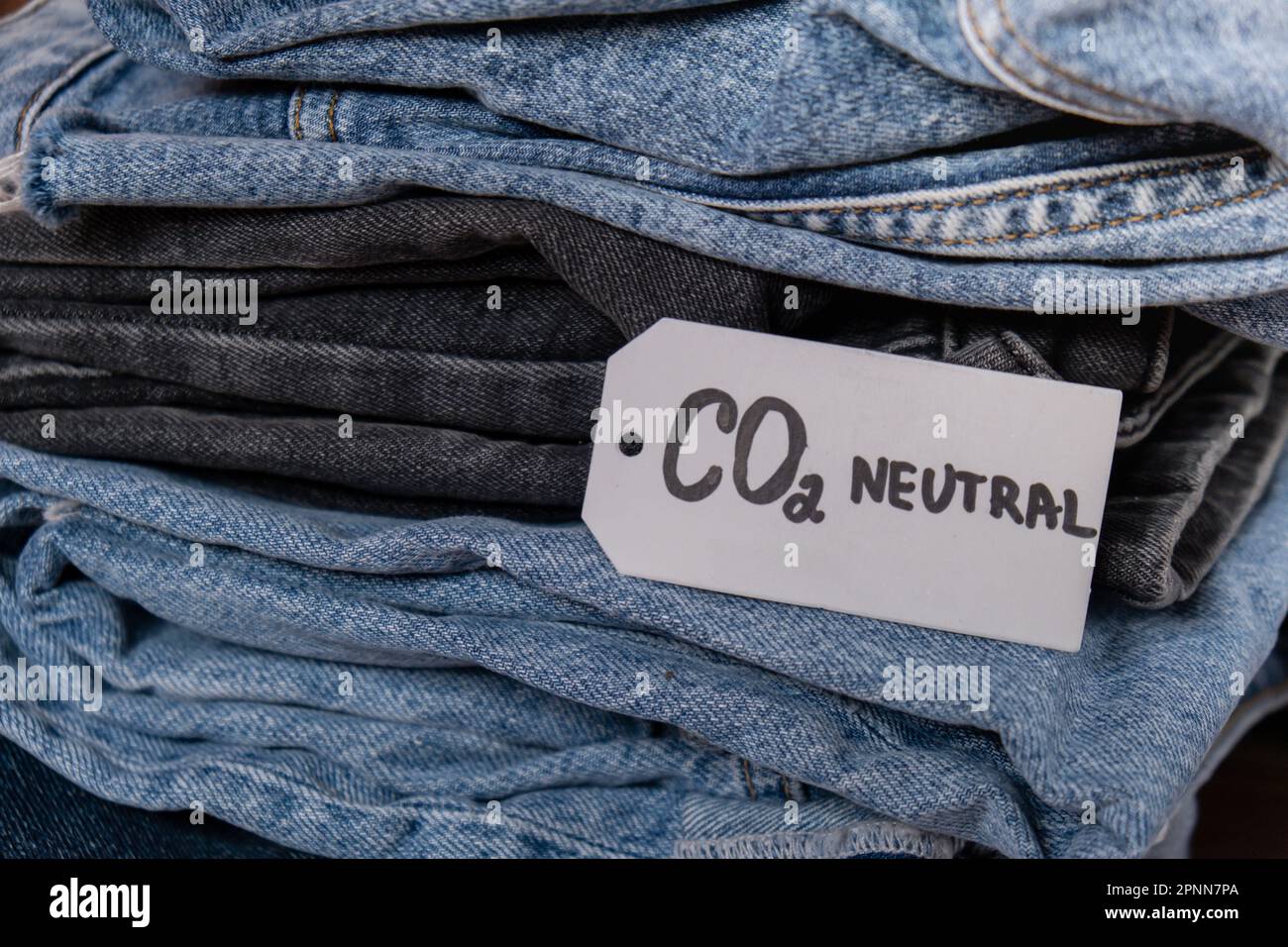 CO2 neutral emission text note on stack of jeans. Ecology nature friendly,  climate change, green fuel and earth protect concept. Carbon emission paper  recycled label. Natural organic jeans clothing with CO2 neutral