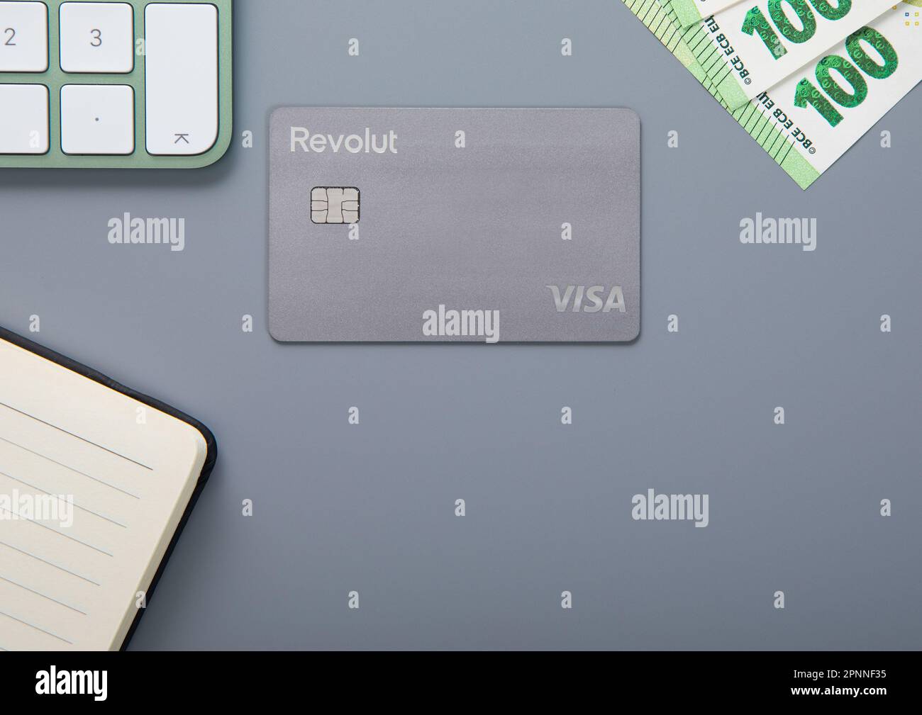 LONDON,UK - NOVEMBER 18, 2022: Revolut visa contactless card with bitcoin on grey with keyboard and 100 euro bill. Top view. Stock Photo