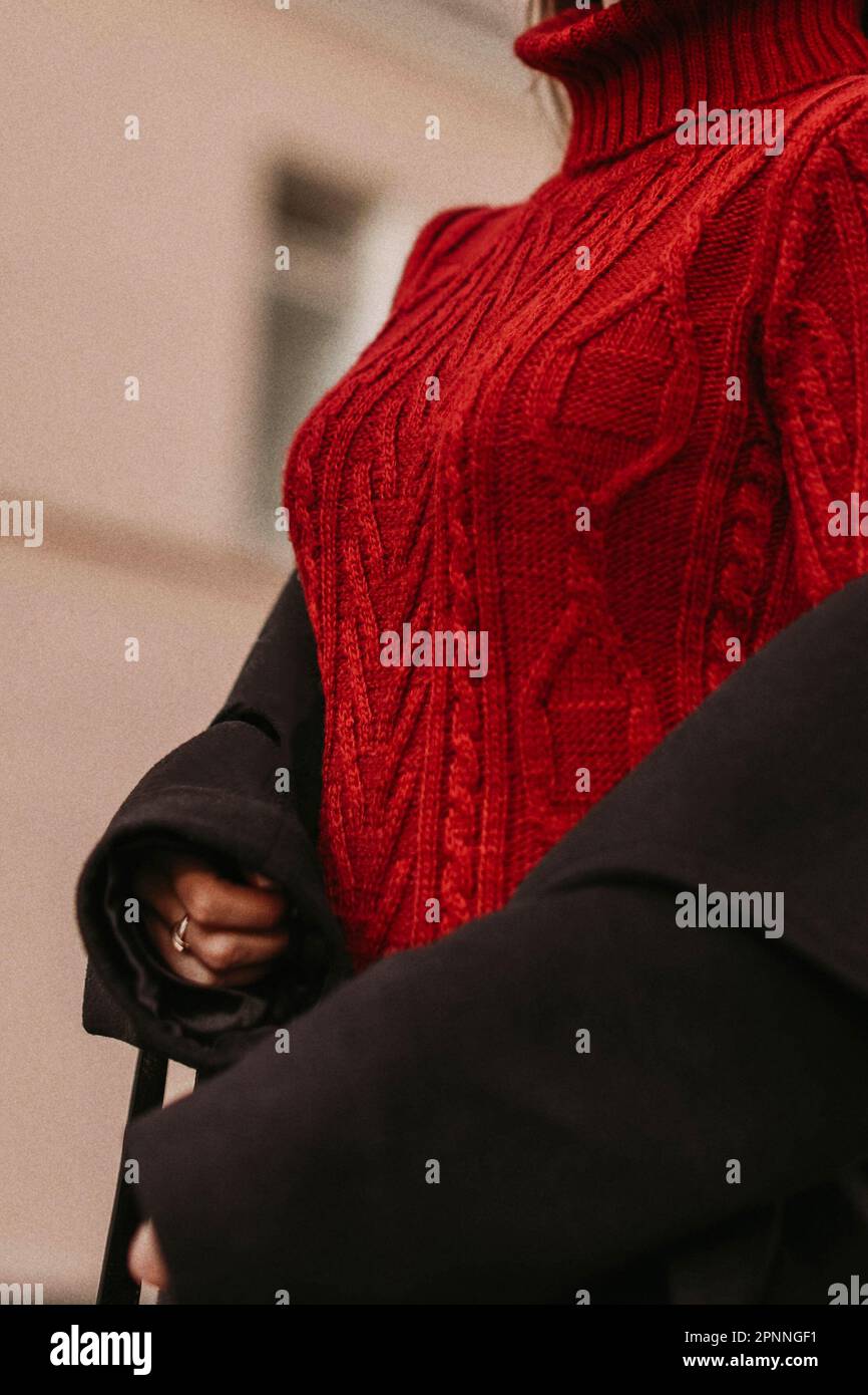 Female figure in the red warm knitted sweater and black coat. Outdoor portrait in daylight. Autumn winter street style cloth concept Stock Photo