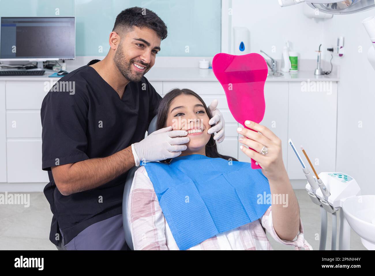 Happy Hispanic dentist and teenager smiling and looking in mirror