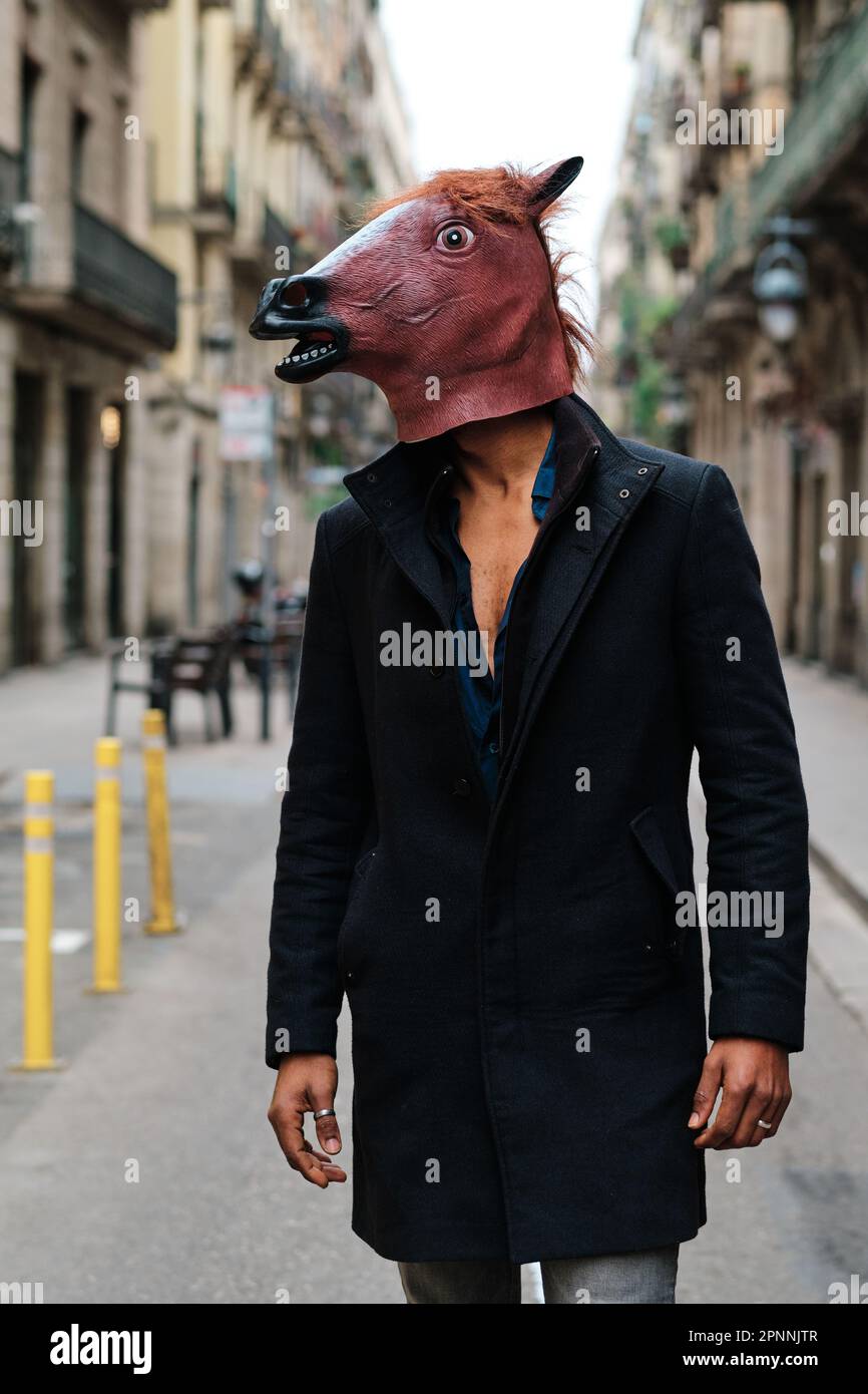 Stylish man wearing a horse mask while standing outdoors on the street