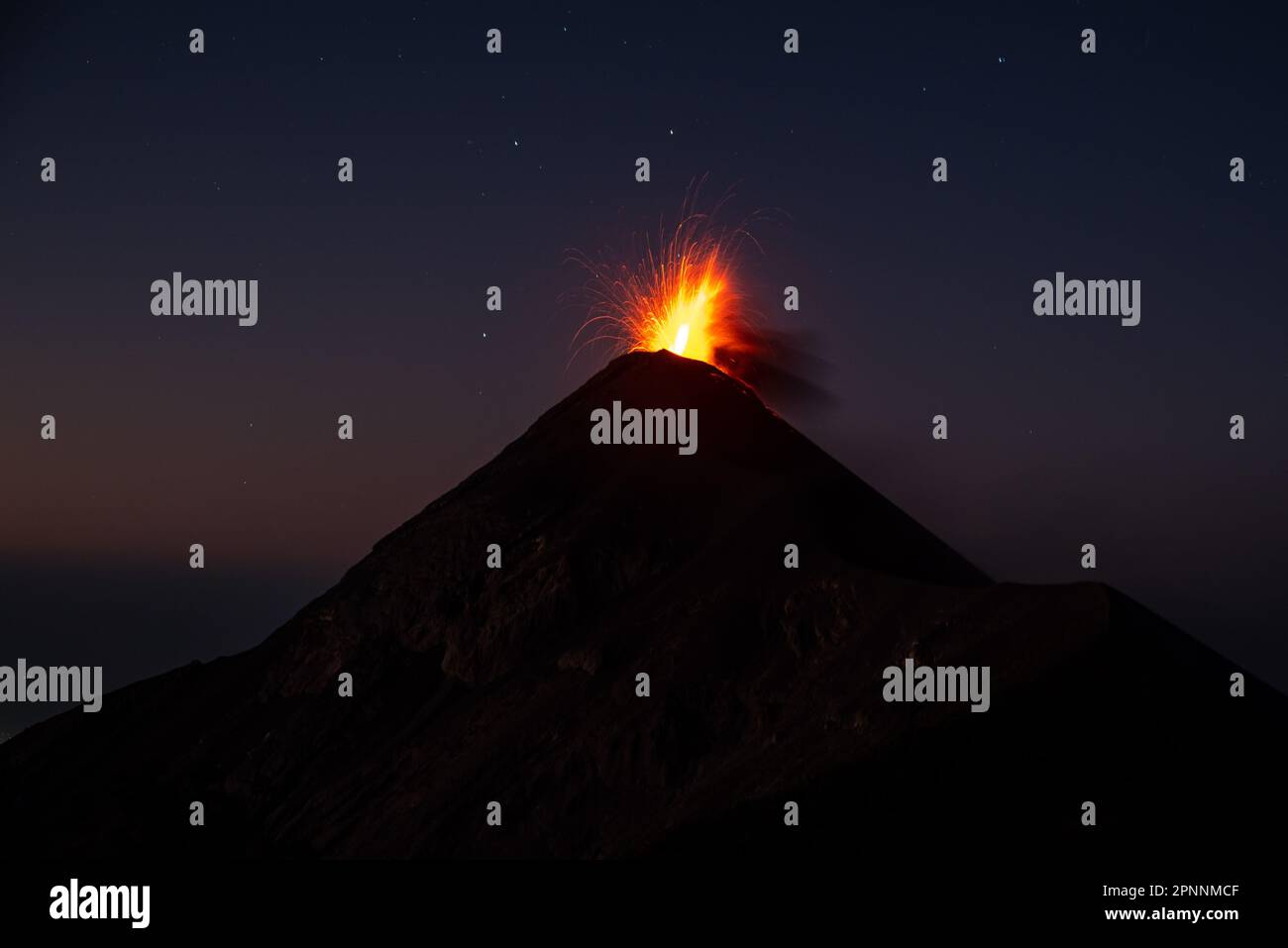 A dramatic shot of a volcanic eruption, with a cloud of ash and lava ...